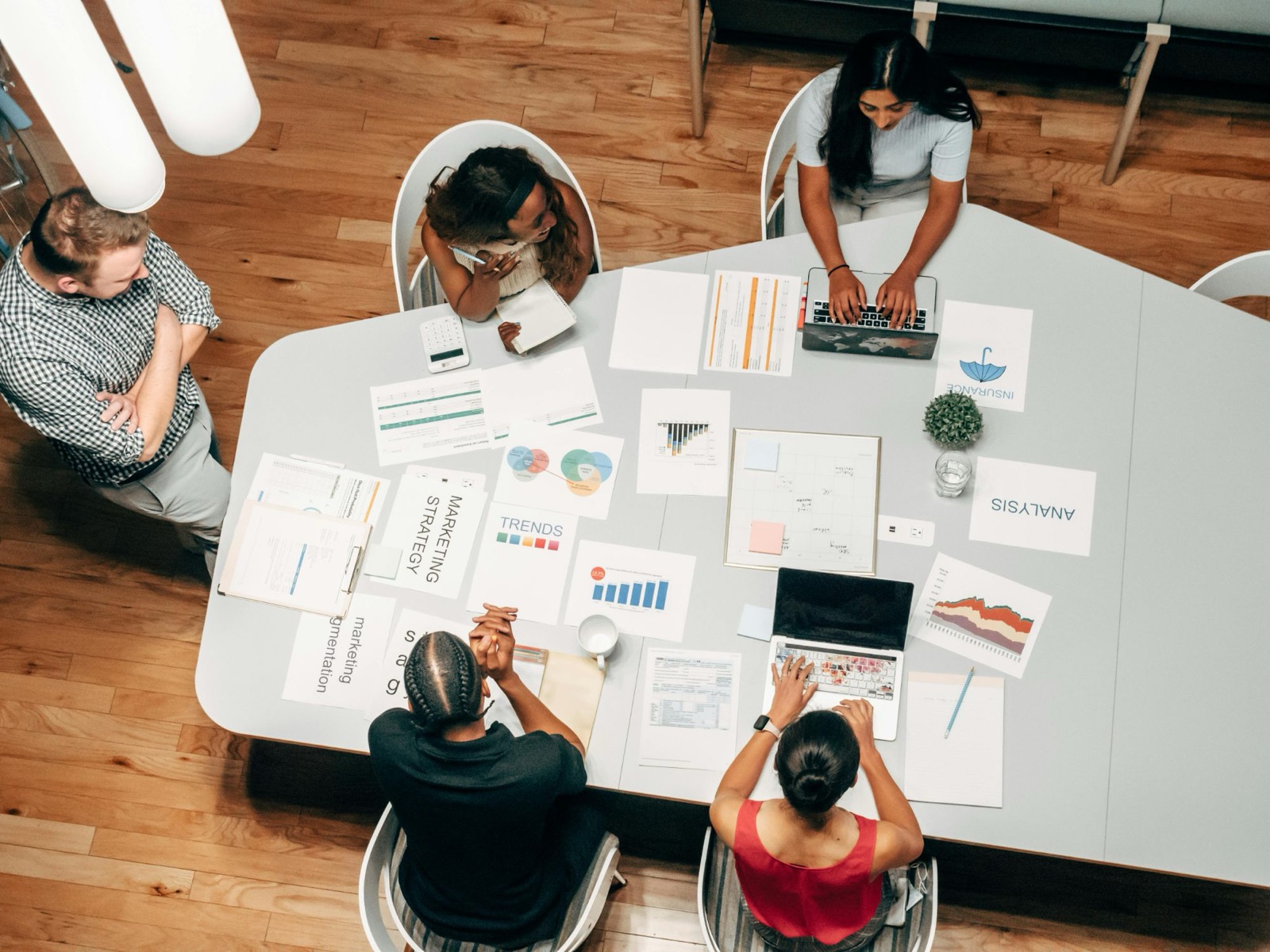 Overhead view of the Affinity Marketing team working around a table covered in marketing strategy, trends and analysis documents